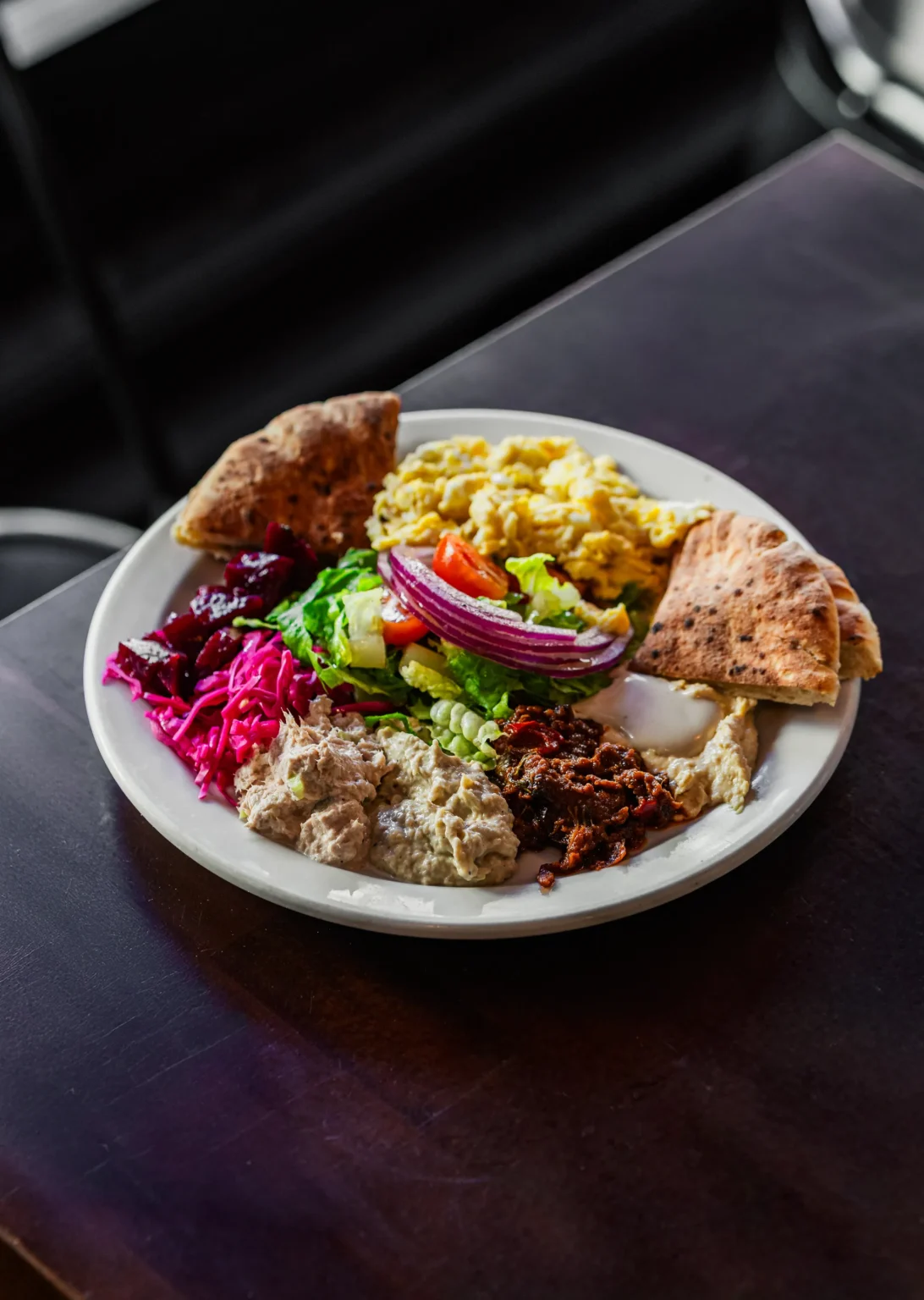 Mediterranean platter with pita, hummus, salads, and scrambled eggs
