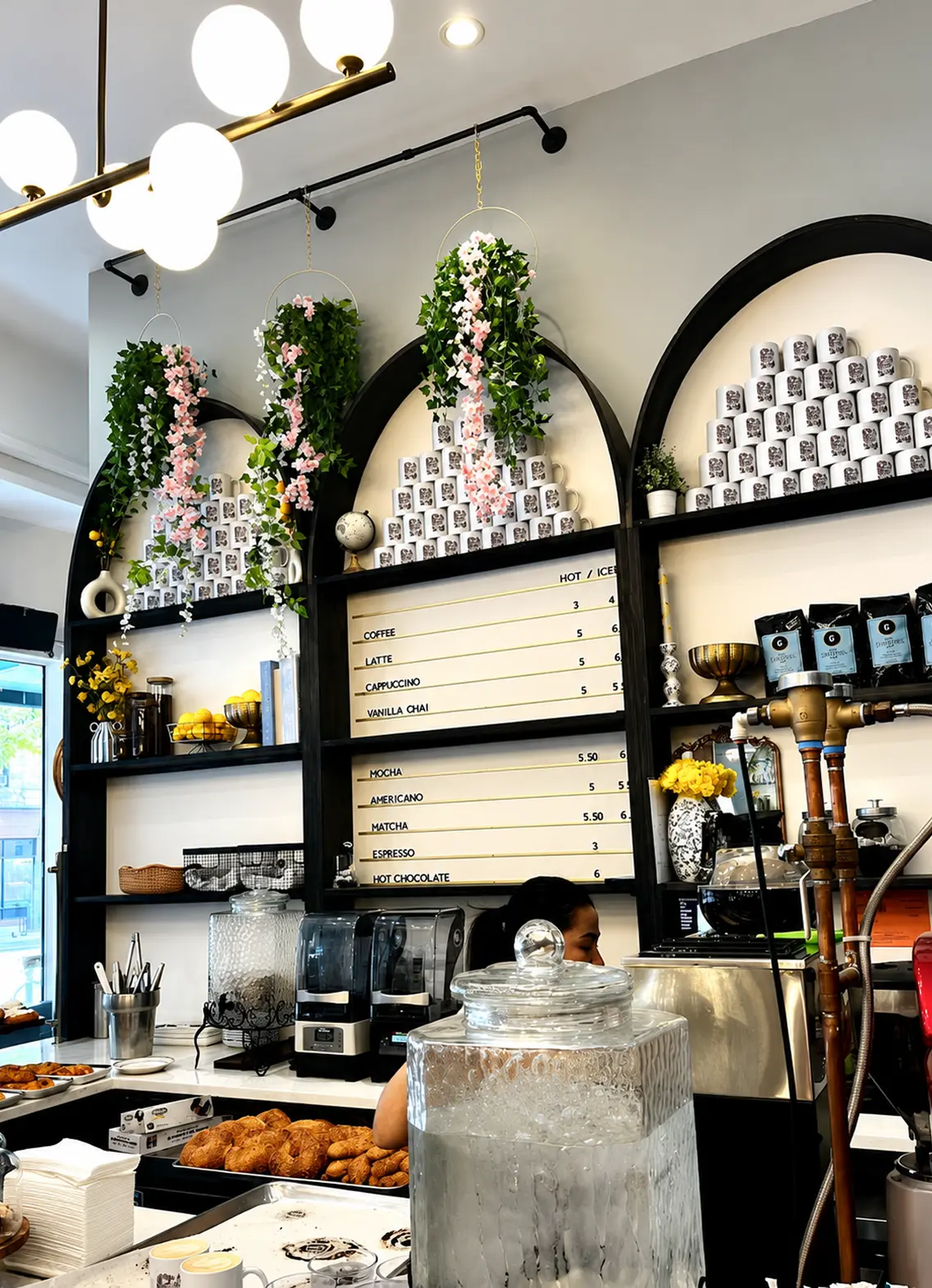 A cozy café interior with arched shelves, floral decorations, and a menu board listing drinks.