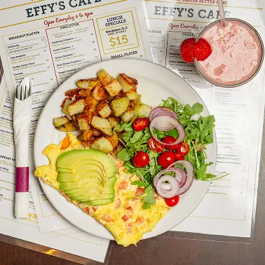 A plate of breakfast omelette, hash browns, and salad sits on a menu at Effy's Cafe.